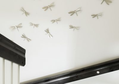 Portaikon seinässä sudenkorento-koristeita.