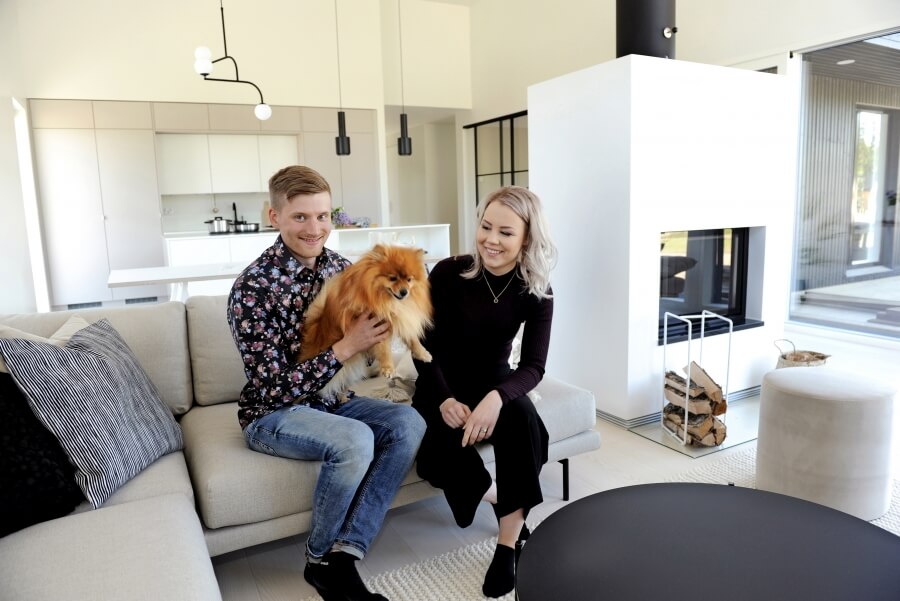 Asuntomessuille rakentuneen kodin onnelliset omistajat olohuone keittiön uopeassa yhdistelmässä perheen koiran kanssa.