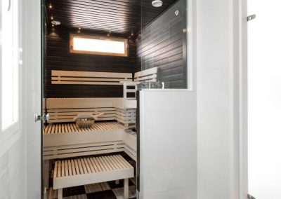 Mustavalkoinen pesuhuone ja sauna, jossa mustavalkoruutuinen lattialaatoitus.