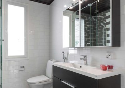 Mustavalkoinen WC/pesuhuone, jossa mustavalkoruutuinen lattialaatoitus. Musta kattopaneeli ja kaapiston ovet.